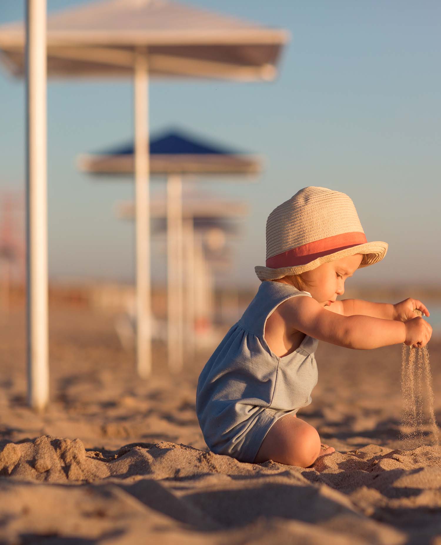 Kid,In,A,Hat,Playing,With,Sand,On,The,Beach