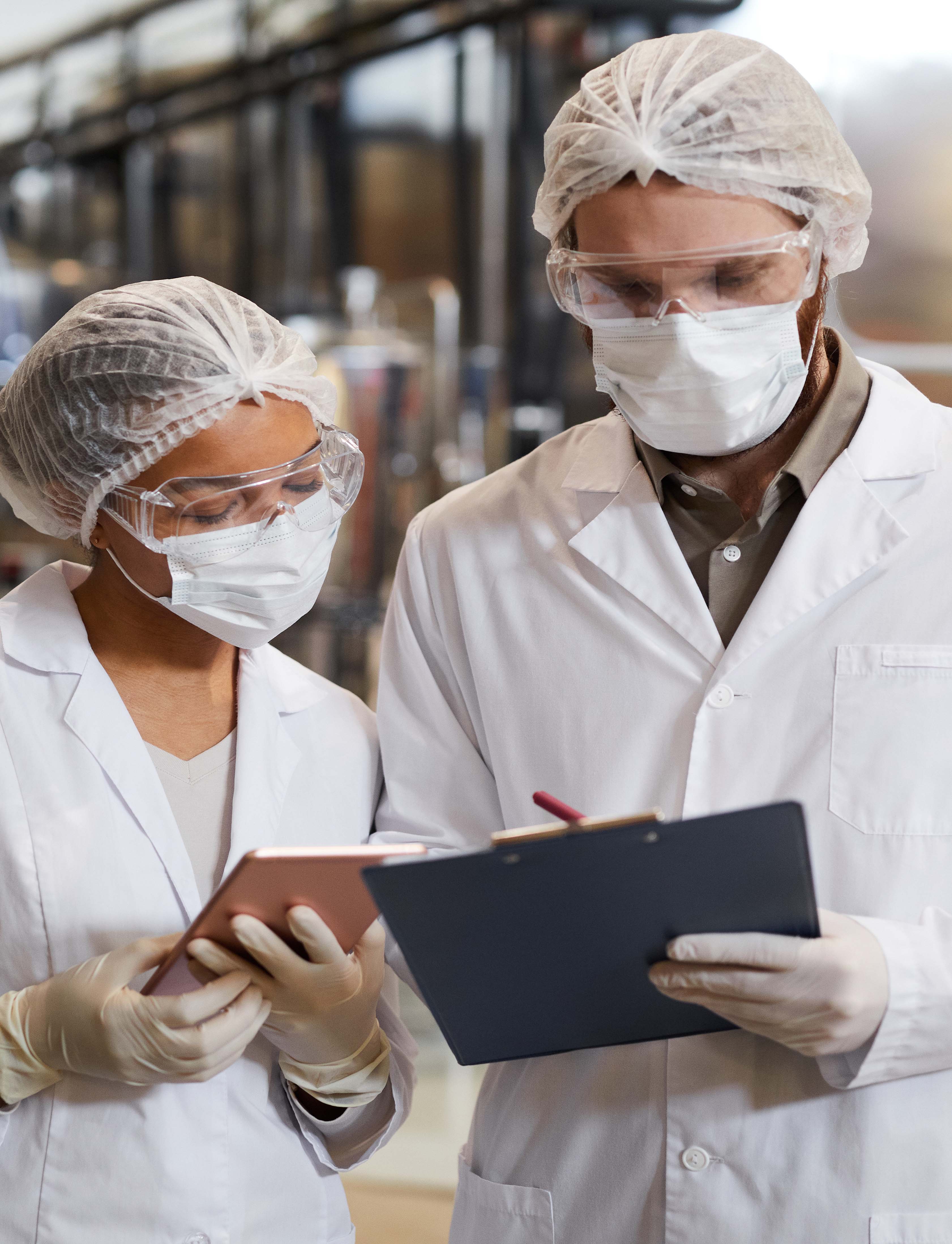 Waist,Up,Portrait,Of,Two,Workers,Wearing,Masks,And,Lab